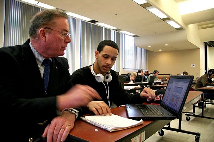 UP TO SPEED: Joe McNamara, left, principal of Pawtucket Alternative Learning Program, works with a student. Also a state representative, McNamara has proposed a statewide policy for online education. / PBN PHOTO/MICHAEL PERSSON
