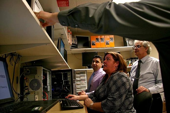 IN DEMAND: Director of Information Technology Issy Ramos, above wearing a tie and glasses, supervises technicians at Bentley Information Technology Systems. / PBN PHOTO/MICHAEL PERSSON