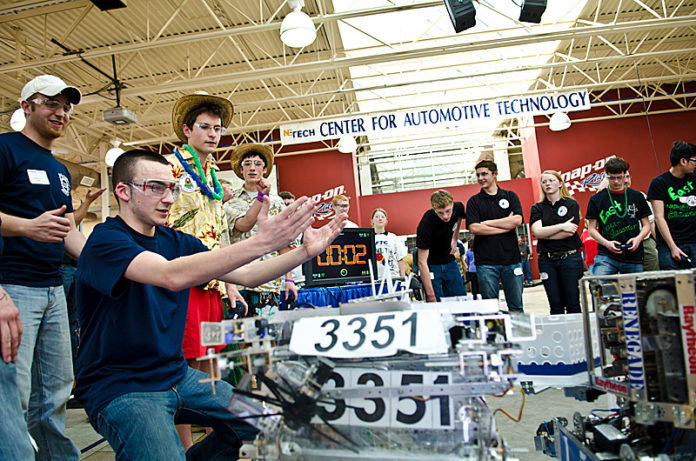 Teams from Burrillville High School, on left in blue shirts, and Mt. Hope High School in Bristol, in Hawaiian shirts, compete Feb. 4 in the FIRST Tech Challenge at the New England Institute of Technology. More than 30 Rhode Island high school teams joined in the competition, which encouraged students to learn how to design, build and program an original robot. The teams then competed against each other using a sports model. This was the sixth year that NEIT has hosted the competition, held at the school’s center for automotive technology in Warwick. / COURTESY GEORGE MARCHANT