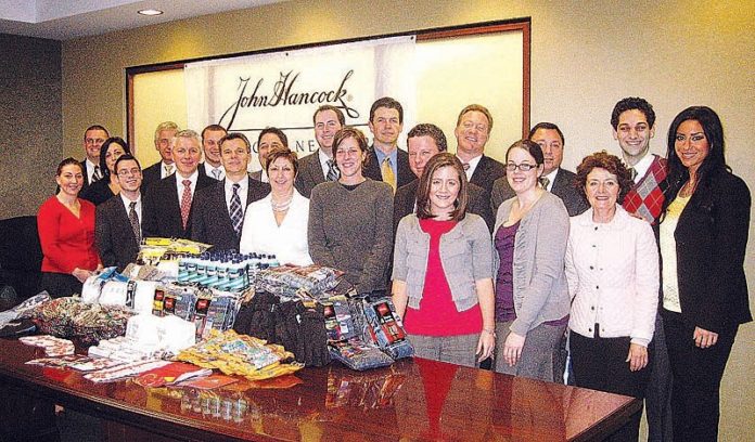 EMPLOYEES AT John Hancock Financial Network – Independence Financial Partners are joined by House of Hope Executive Director Jean Johnson (front row, fifth from left) and Associate Director Monica Spicer (front row, fifth from right). On display in the foreground are the items the employees collected for the nonprofit’s clients.