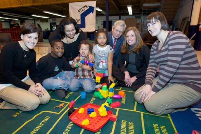 BANKNEWPORT VICE PRESIDENT and Newport Branch Manager Jennifer Pratt (seated, second from right) joined Baby Steps President Dr. Charles Shoemaker (kneeling, center) for a recent Baby Steps session for children and parents held at the Florence Gray Center in Newport. Ydalis Perez and her three children were enjoying the interactive activities with Bradley School representatives, Rebecca Berger (kneeling left) and Rochelle Fritz (kneeling right). / COURTESY BANKNEWPORT