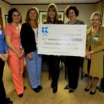 DAWN CORMIER, center, of the American Cancer Society, is presented with a $25,000 donation by Kent Hospital staff, remaining, from left: Diane Nagel, Coordinated Care Unit; Cristen Gardiner, The Breast Health Center at Kent; Kim McDonough, manager, The Breast Health Center at Kent; Kent Hospital President and CEO Sandra Coletta; Candace Dyer, physician director, The Breast Health Center at Kent; and Andrea Norman, Coordinated Care Unit.