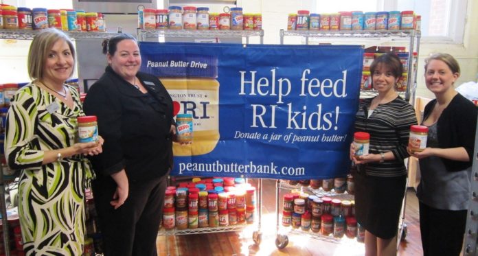 FROM LEFT, Washington Trust Vice President Sharon Morgan, branch managers Wendy Bazydlo and Helena Nulick, and executive director of the Westerly-based Johnnycake Center Elizabeth Pasqualini stand before peanut butter collected during the annual Washington Trust peanut butter drive. / COURTESY THE WASHINGTON TRUST CO.
