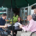 DINING OUT: Newport Harbor Company&rsquo;s Ben Emmons, marketing account manager, left, and Kristin Fahey, human resource manager, center, discuss dining options with Bowen's Wine Bar & Grille&rsquo;s Bob Schone, dining room supervisor, right foreground, and waiter Brian White. / PBN PHOTO/CATIA CUEN