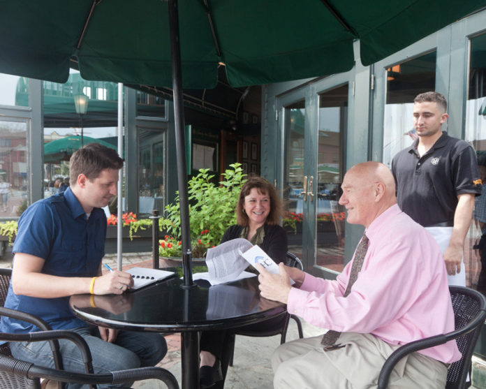 DINING OUT: Newport Harbor Company’s Ben Emmons, marketing account manager, left, and Kristin Fahey, human resource manager, center, discuss dining options with Bowen's Wine Bar & Grille’s Bob Schone, dining room supervisor, right foreground, and waiter Brian White. / PBN PHOTO/CATIA CUEN
