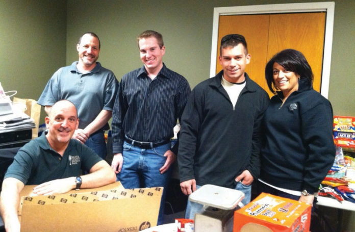 BRISTOL COUNTY SAVING BANK employees recently sent 581 pounds of food and hygiene items to local soldiers currently serving in Afghanistan. Helping to pack and send the items, from left to right, are Rick Lewis, Nick DeBaggis and Mike Murteira of Bristol County Savings Bank; Pvt. Ryan Hetu of R.I. National Guard’s Company C, 1st battalion, 143rd infantry regiment, and Elizabeth M. Yebba of Bristol County Savings Bank.