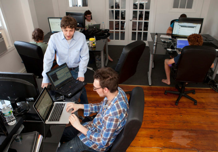 LIVING OUT A FANTASY: A team of young entrepreneurs at Fanium could revolutionize the way fantasy-sports players digest
information. Above, Fanium CEO Grant Gurtin, standing, speaks with Erik Larson at the tech startup's Providence office. / PBN PHOTO/DAVID LEVESQUE LIVING OUT A FANTASY: A team of young entrepreneurs at Fanium could revolutionize the way fantasy-sports players digest
information. Above, Fanium CEO Grant Gurtin, standing, speaks with Erik Larson at the tech startup's Providence office. / PBN PHOTO/DAVID LEVESQUE