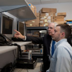 Seeing opportunity in cybersecurity THE BEST OFFENSE: NetCenergy President Don Nokes, background, works with intern Joey Vierra. / PBN PHOTO/CATIA CUEN