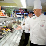 ALL THE RIGHT FOODS: Chef Daniel Van Etten leads a tour of the healthy food offerings at Lifespan&rsquo;s cafeteria, including many kinds of fruit. / PBN PHOTO/
RUPERT WHITELEY