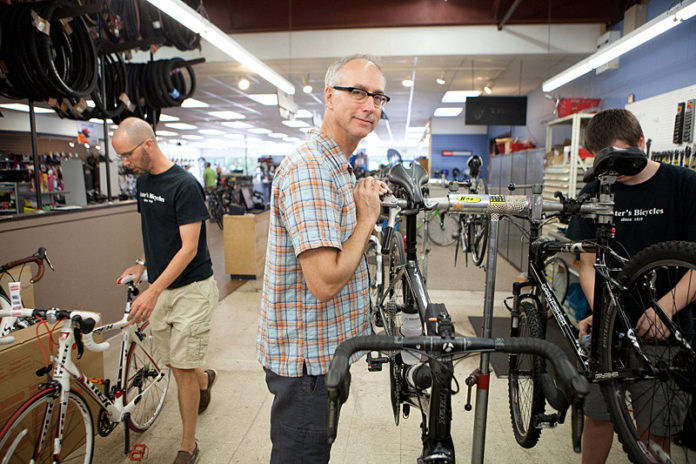 CHAIN OF COMMAND: Caster's Bicycles and Fitness owner Reed Caster, center, is the third-generation owner of the shop. He's pictured above with salesperson John Schmidt, left, and mechanic James Groh. / PBN PHOTO/RUPERT WHITELEY