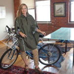 CLEVER IDEA: Cleverhood owner Susan Mocarski shows off her Providence-based company’s apparel, which aims to keep bicycle commuters dry while being stylish. / PBN PHOTO/DAVID LEVESQUE