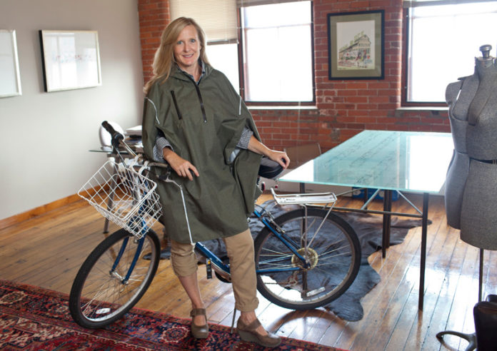 CLEVER IDEA: Cleverhood owner Susan Mocarski shows off her Providence-based company’s apparel, which aims to keep bicycle commuters dry while being stylish. / PBN PHOTO/DAVID LEVESQUE CLEVER IDEA: Cleverhood owner Susan Mocarski shows off her Providence-based company’s apparel, which aims to keep bicycle commuters dry while being stylish. / PBN PHOTO/DAVID LEVESQUE