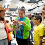 MAKING CONNECTIONS: Middle schoolers at Providence’s Nathan Bishop School, from middle left, Alondra Gomes, Gabriel Rodriguez, Jasmin Fields and Lauren Thornton take part in a PASA AfterZone recruitment fair. In charge of the “Conservation Station” part of the program is Becca Buckler, at left. / PBN PHOTO/RUPERT WHITELEY