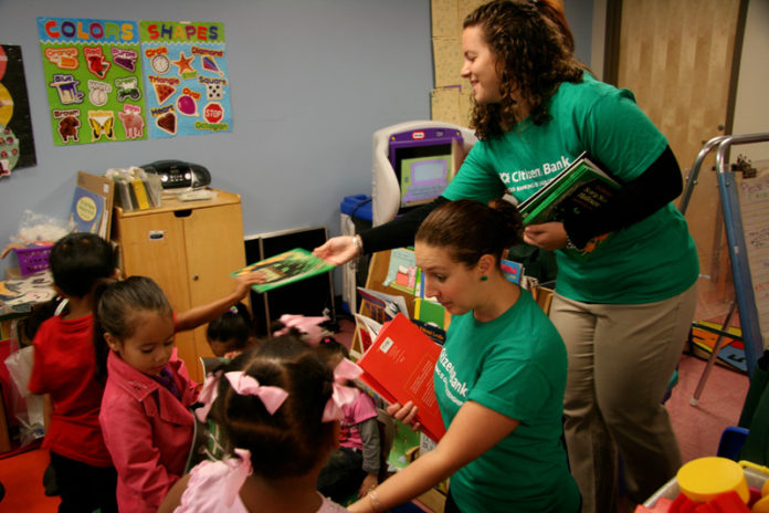 DELIVERING THE GOODS: Citizens Bank employees hand out books collected from co-workers to pupils at Children’s Friend. / PBN PHOTO/MICHAEL PERSSON