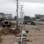 CLEANING UP: A machine clears sand off Atlantic Avenue in the Misquamicut area of Westerly. While most Rhode Island businesses were able to escape Hurricane Sandy&rsquo;s wrath, many along the coast are faced with a tough rebuilding process. / PBN PHOTO/BRIAN MCDONALD