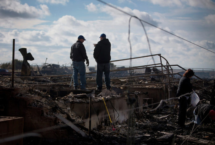 RESIDENTS SURVEY the damage to their home in the Breezy Point neighborhood of the Queens borough of New York City on Wednesday, Oct. 31, 2012. / BLOOMBERG FILE PHOTO/SCOTT EELS