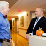 PROVIDING CARE: Charles P. Iacono, right, vice president of philanthropy at Home and Hospice Care of Rhode Island, speaks with Dr. Edward Martin, chief medical officer at the nonprofit. Iacono says he&rsquo;s seen increased support from corporations recently. / PBN PHOTO/NATALJA KENT