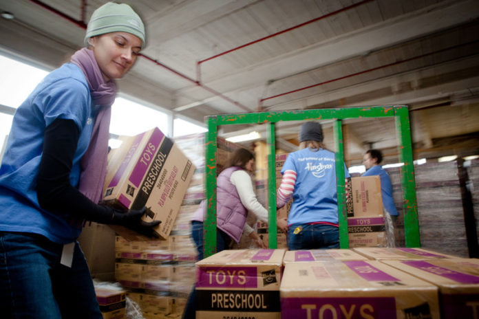Team Hasbro volunteer Ariel Madera, left, lifts a box onto a pallet jack Nov. 27, in preparation for a company donation to Rhode Island families of 25,000 toys and games. They will be distributed to Rhode Island Community Action Association agencies across the state. Children who will benefit are involved with or receive assistance from the Rhode Island Department of Human Services or the R.I. Department of Children, Youth & Families. / COURTESY STEPHANIE ALVAREZ EWENS