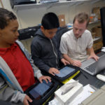 WELCOME TO THE INFORMATION AGE: Community Prep computer-science teacher Brendan Corley, right, helps sixth-graders Michael Johnson III, left, and Jeffrey Gao set up email with their new iPads. / PBN PHOTO/BRIAN MCDONALD
