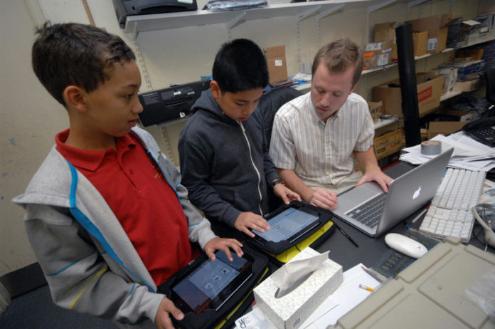 WELCOME TO THE INFORMATION AGE: Community Prep computer-science teacher Brendan Corley, right, helps sixth-graders Michael Johnson III, left, and Jeffrey Gao set up email with their new iPads. / PBN PHOTO/BRIAN MCDONALD