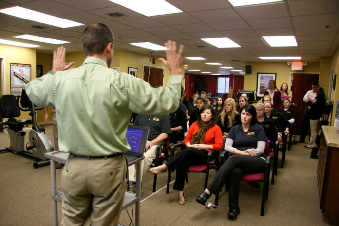 ALL TOGETHER NOW: Elite Physical Therapy Vice President of Operations Jason Harvey leads staff through an in-house education session, one of many that the company puts on. / PBN PHOTO/MICHAEL PERSSON