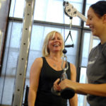 Personal training comes to masses STRENGTH IN NUMBERS: After being founded in Phoenix in 2001, Poliquin Performance was reopened in Rhode Island 2006 following a chance meeting in an East Greenwich gym. Above, co-owner Caroleen Jones, left, works with staffer Janelle Avila in the company’s gym. / PBN PHOTO/BRIAN MCDONALD