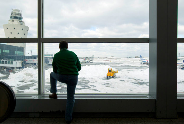 SNOW DELAYS: A TRAVELER WATCHES a crew remove snow in the Central Terminal at LaGuardia Airport in New York. Snow and freezing rain up and down the East Coast have begun to tie up air traffic and make travel difficult in the region. / BLOOMBERG FILE PHOTO/JIN LEE