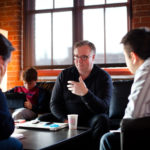 MAKING CONNECTIONS: Shane Lennon, center, a Betaspring mentor and VP of marketing for DimentionU, speaks with 121 Nexus&rsquo; Foster Sayers and Albert Ho. / PBN PHOTO/STEPHANIE ALVAREZ EWENS