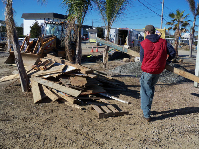 SUMMER DREAMING: A volunteer carries wood scattered by remnants of Hurricane Sandy past the Purple Ape on Winnapaug Road in Westerly. / COURTESY SERVE RHODE ISLAND