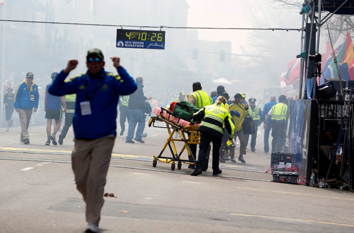 FIRST RESPONDERS rush to where two explosions occurred along the final stretch of the Boston Marathon on Boylston Street in Boston on Monday. Two powerful explosions rocked the finish line area of the Boston Marathon near Copley Square and police said many people were injured.  / KELVIIN MA/BLOOMBERG NEWS PHOTO