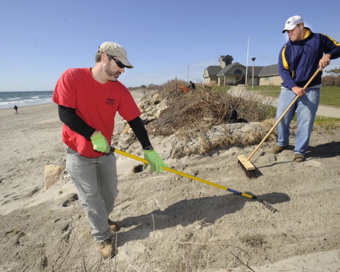 PITCHING IN: Military veterans Matthew Paquette, left, and Jonathan Segal work at Scarborough State Beach in Narragansett on storm cleanup. / PBN PHOTO/MARTIN GAVIN