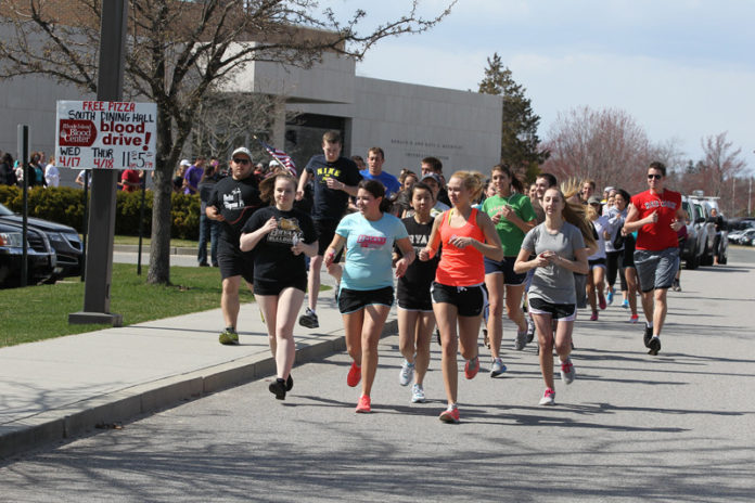Bryant University freshman Ashley Cardona, front, blue T-shirt, joins students and other members of the university community for a one-mile run on campus April 16, in support of those affected by the Boston Marathon attack. Cardona,  an international business major, suggested the run to university officials as a unified show of support against violence and for the families affected by the tragedy. Bryant also observed one minute of silence in memory of those lost or injured in the April 15 bombing near the race’s finish line. / COURTESY DAVE SILVERMAN