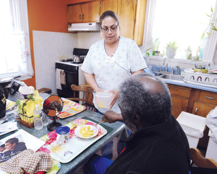 PATIENTS PAYING OFF: Homefront Health Care certified nursing assistant Margarita Feliciano works with a patient. She entered the field in 2011 after being laid off from her banking job. / PBN PHOTO/MARTIN GAVIN