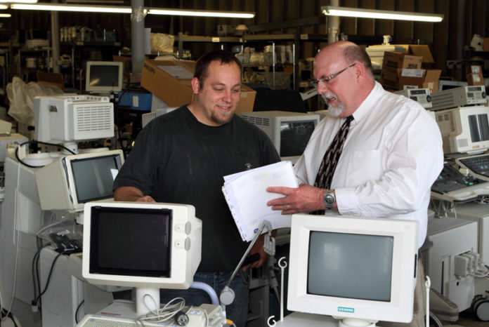 RECYCLED GOODS: Bob Gaw, right, president of Physicians Resource Network, speaks with Steven Hipolito, a sales and logistics employee at the company. According to Gaw, the company’s warehouse has enough equipment to outfit six hospitals. / PBN PHOTO/KATE WHITNEY LUCY RECYCLED GOODS: Bob Gaw, right, president of Physicians Resource Network, speaks with Steven Hipolito, a sales and logistics employee at the company. According to Gaw, the company’s warehouse has enough equipment to outfit six hospitals. / PBN PHOTO/KATE WHITNEY LUCY