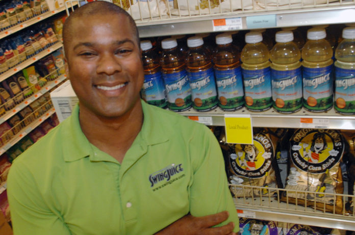 JUICED UP: Jon Mason shows off a display of Swing Juice in Providence’s East Side Marketplace, the product of his seven-year-old effort inspired by a golf outing with a friend. / PBN PHOTO/BRIAN MCDONALD