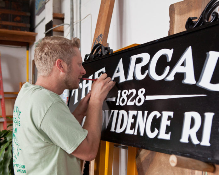 SIGN OF THINGS TO COME: Shawn Gilheeney, above, is co-owner of Providence Painted Signs, a company founded by three local artists with an eye for traditional typefaces. It’s currently tackling work for businesses going into the new Arcade. / PBN PHOTO/TRACY JENKINS