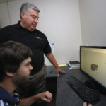 SERVICE MAN: Vietnam combat veteran and Veterans Assembled Electronics owner John Shepard, standing, works with mechanical engineer Michael Ratigan. / PBN PHOTO/BRIAN MCDONALD