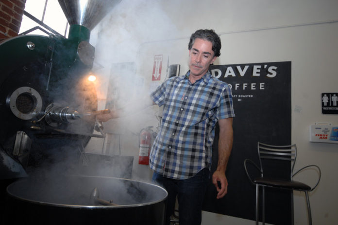 ROASTED: Dave’s Coffee owner Dave Lanning unloads the roasting machine after a batch of coffee beans finished roasting. The company began as an espresso bar in 2003. / PBN PHOTO/BRIAN MCDONALD