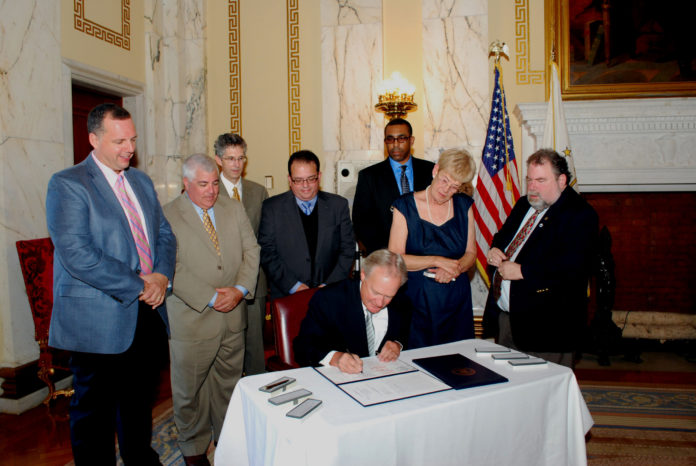 GOV. LINCOLN D. CHAFEE SIGNED legislation expanding the enterprise zone in Pawtucket as officials from Tunstall and the city looked on. / COURTESY R.I. GENERAL ASSEMBLY