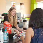 COOLING OFF? Danielle Mott, assistant manager at Hot and Cold Frozen Yogurt in Providence, serves a customer. While national frozen yogurt chains are growing their presence in Rhode Island, independent stores such as Hot and Cold are finding a market. / PBN PHOTO/TRACY JENKINS