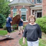 MOVING OUT: Marion Thayer, 69, and her husband, Rob, are moving out of their North Kingstown home and into a duplex condominium. Behind her, employees from moving company Astro of New England handle some of the Thayers’ belongings. / PBN PHOTO/TRACY JENKINS