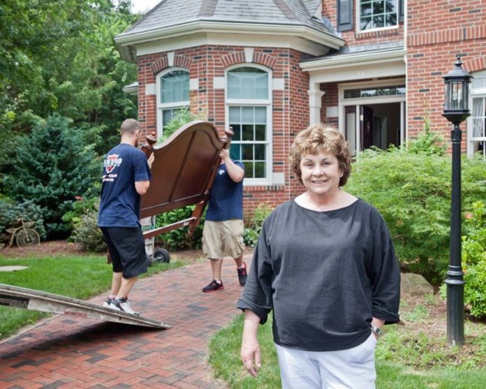 MOVING OUT: Marion Thayer, 69, and her husband, Rob, are moving out of their North Kingstown home and into a duplex condominium. Behind her, employees from moving company Astro of New England handle some of the Thayers’ belongings. / PBN PHOTO/TRACY JENKINS