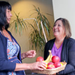 EATING THE TALK: United Natural Foods provides free organic fruit in its break rooms as part of its commitment to employees. Above, Joni Weglein, left, and Karen O&rsquo;Brien take advantage of the offering. / PBN PHOTO/NATALJA KENT