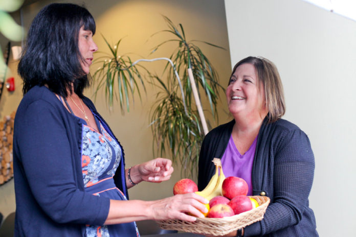 EATING THE TALK: United Natural Foods provides free organic fruit in its break rooms as part of its commitment to employees. Above, Joni Weglein, left, and Karen O&rsquo;Brien take advantage of the offering. / PBN PHOTO/NATALJA KENT