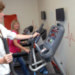 Self-insurance boosts firm’s wellness efforts AS PROGRAM GROWS, HEALTH IMPROVES: Carousel Industries’ retooled wellness program has had an effect on its employees, more of whom take part in physical activities, including using the on-site fitness center. Working out are Diane Stanley, left, and Anita Anderson. / PBN PHOTO/BRIAN MCDONALD