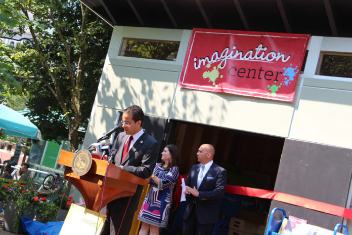 Providence Mayor Angel Taveras, at podium, helps unveil the new “Imagination Center” in Burnside Park on Aug. 22. The center was created with a grant from Southwest Airlines and will serve as a new place for family friendly activities in the park, including arts and crafts and interactive play. Joining Taveras are Megan Wood, senior manager of community outreach at Southwest Airlines and Cliff Wood (no relation) of the Downtown Providence Parks Conservancy. / COURTESY PROVIDENCE MAYOR’S OFFICE