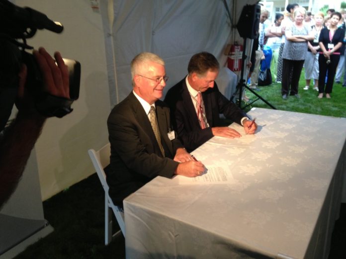 CARE NEW ENGLAND PRESIDENT AND CEO DENNIS KEEFE, left, and Interim President and CEO Arthur DeBlois III of Memorial Hospital sign the partnership agreement that officially binds Memorial to the CNE network at a ceremony held Tuesday on Memorial's Pawtucket campus. / PBN PHOTO/RICHARD ASINOF