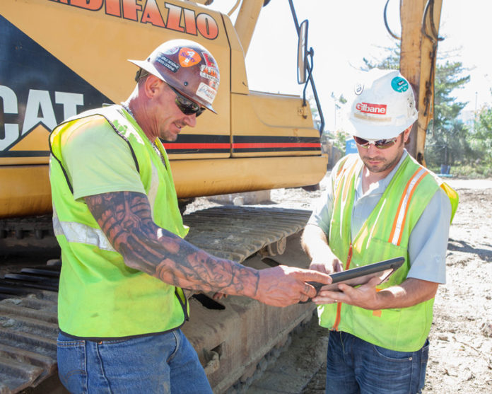 DIGITAL BUILDING: Gilbane Construction Co. foreman Don Welshman, left, and superintendent Adam Bernier use a tablet device on a work site. Gilbane is among the firms utilizing new software. / PBN PHOTO/TRACY JENKINS