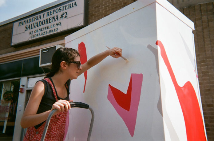 Equipped with disposable cameras, elementary school students taking part  in a summer program through Brown University explored the Olneyville  neighborhood. Above, artist Lauren Smith is painting an electrical box in Olneyville Square as part of Providence’s Art Transformer Project. The student photos were on display last week at William D’Abate Elementary School in Providence. / COURTESY DAVANNA JACKLEY