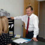 PLANNING AHEAD: Entwistle Financial Life Planning founder Bill Entwistle says the elderly are susceptible to scams because of their age and their accumulated assets. Above, he speaks with paraplanner Terry Hazel in his South Kingstown office. / PBN PHOTO/BRIAN MCDONALD